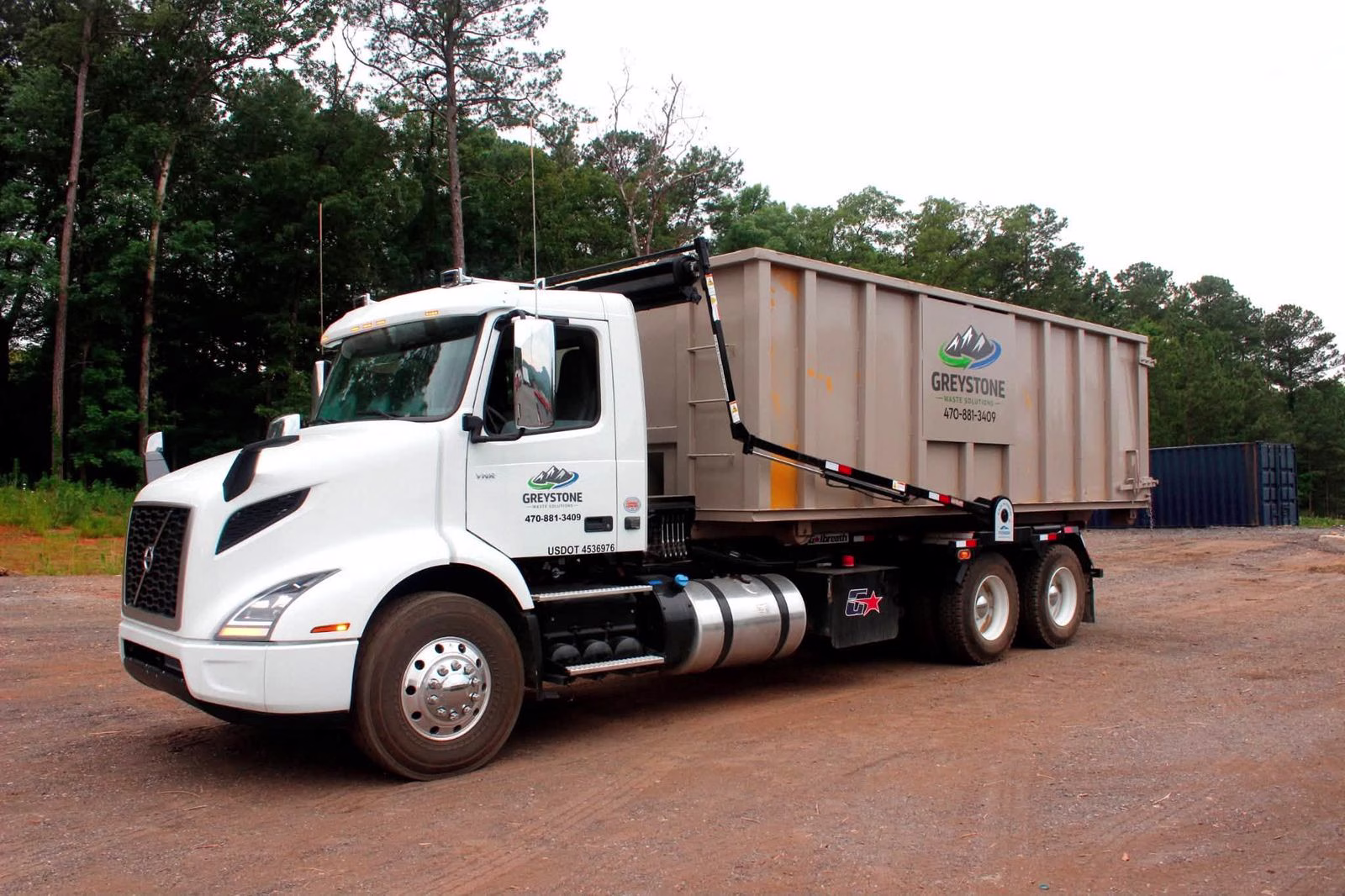 Greystone Waste Solutions roll-off truck delivering a dumpster in northwest Georgia